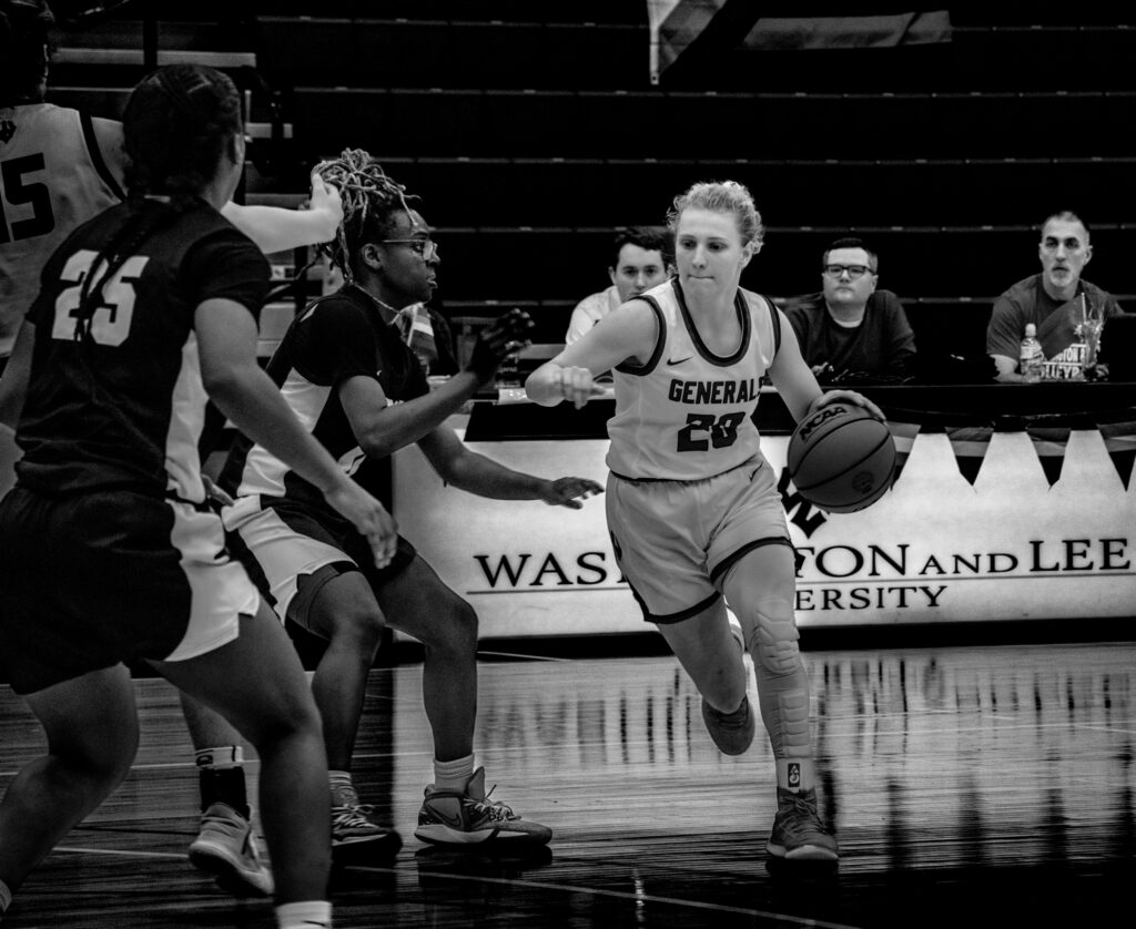 W&L female basketball player dribbling ball around other team